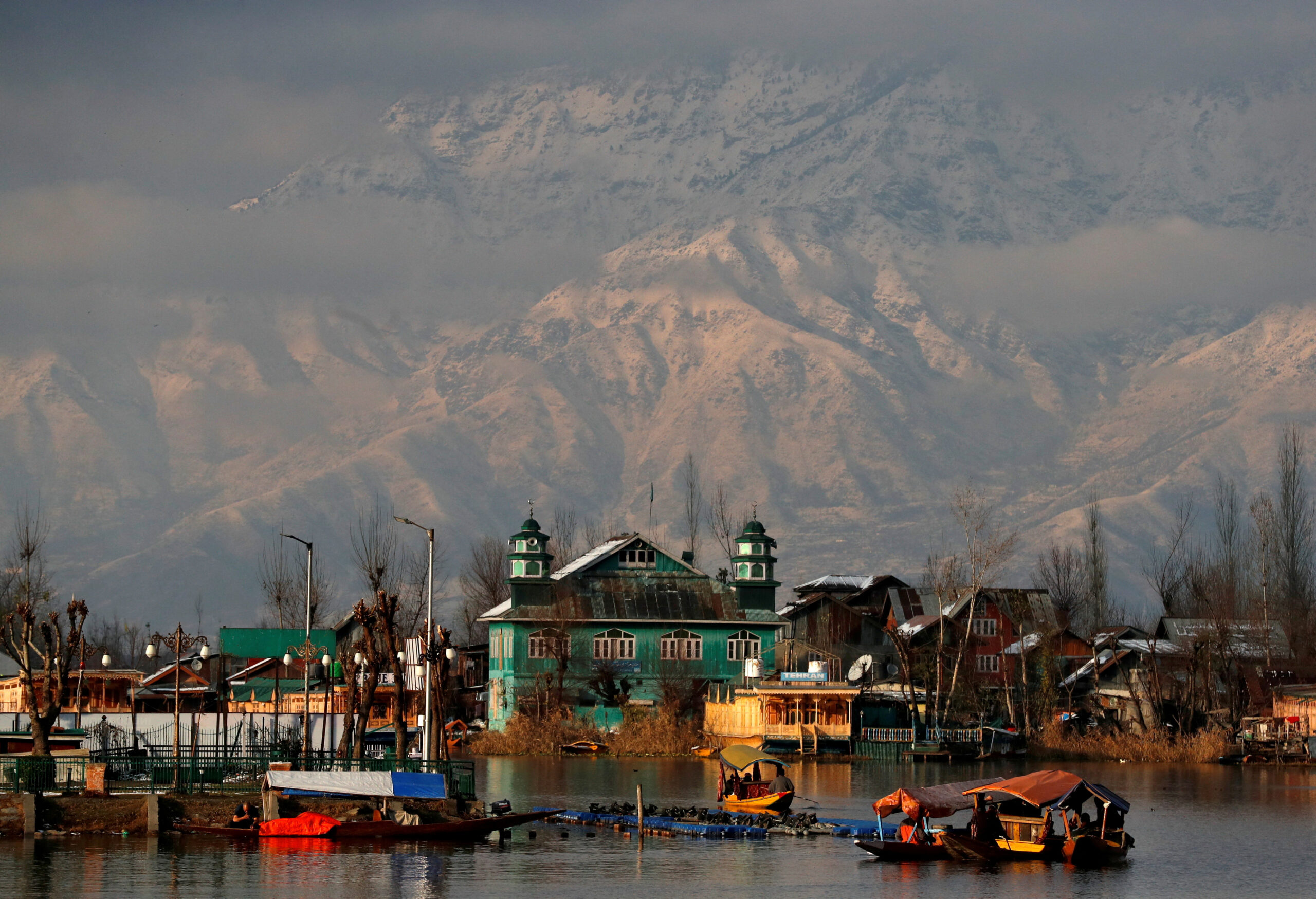 FILE PHOTO: People row their boats in the waters of Dal Lake with the backdrop of snow-covered mountains after a snowfall in Srinagar December 12, 2020. REUTERS/Danish Ismail/File Photo